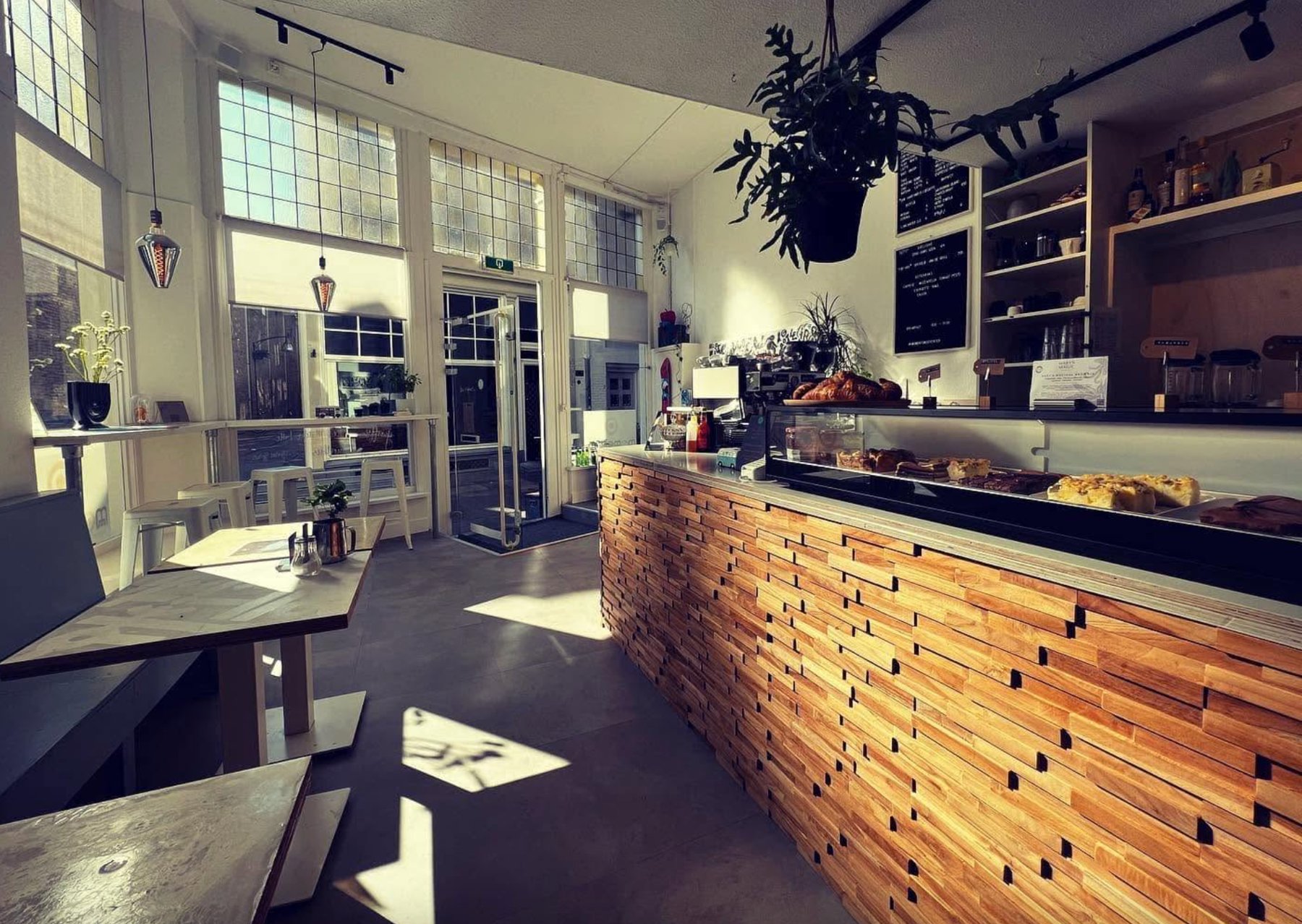Zonlicht door het glas-in-lood bij Momentum, met de houten bar en huisgemaakt gebak